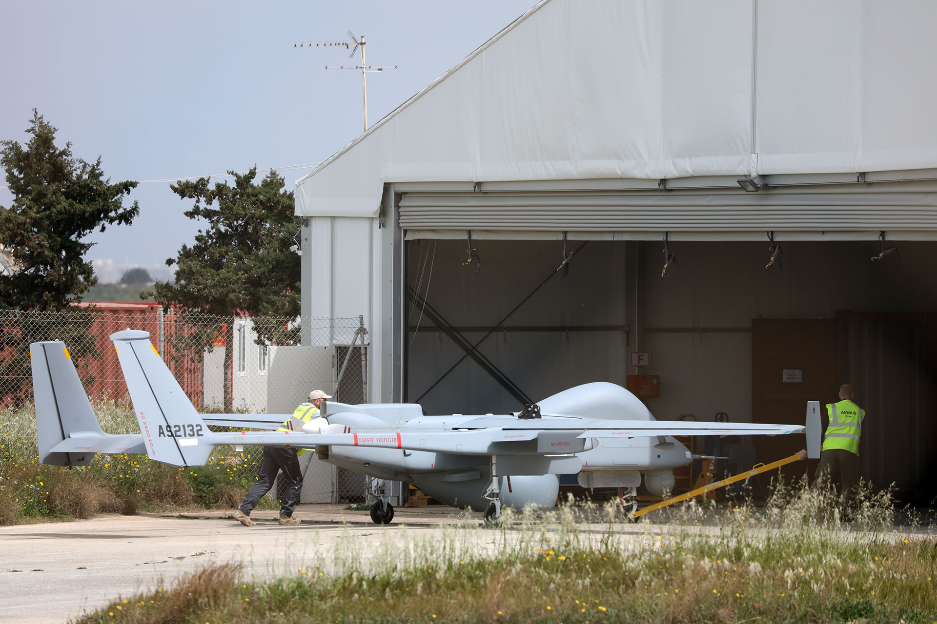 Airbus drone operators push the drone inside its hangar.