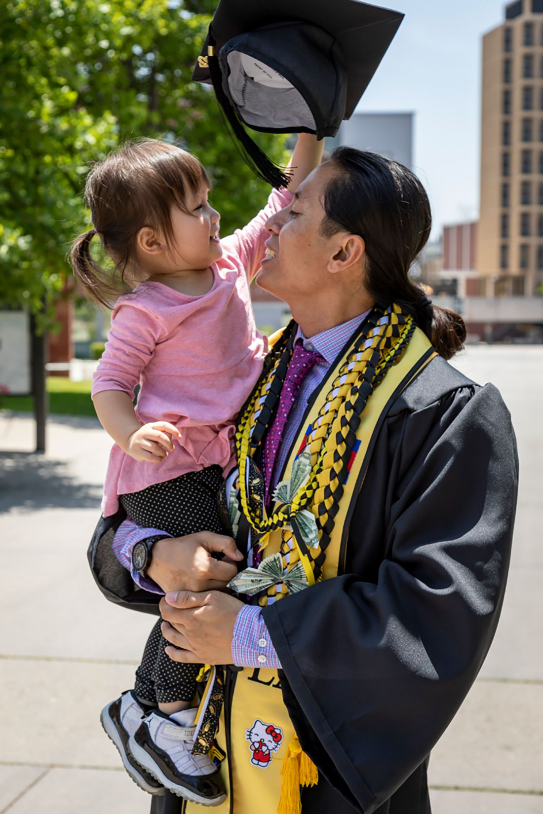 Thaisan N. wearing graduation robes holding a baby